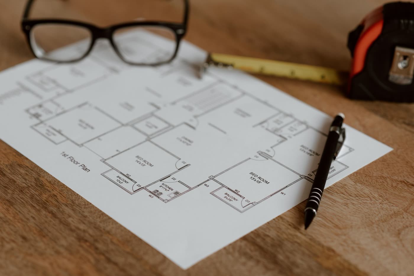 A ruler, pencil and glasses resting on a printed house plan