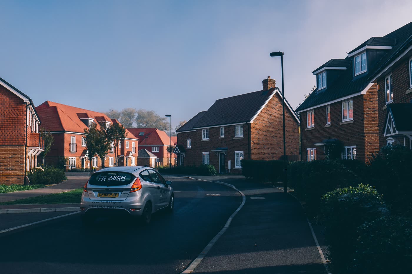 A UK new-build estate street of brick houses with shared access and on-plot parking