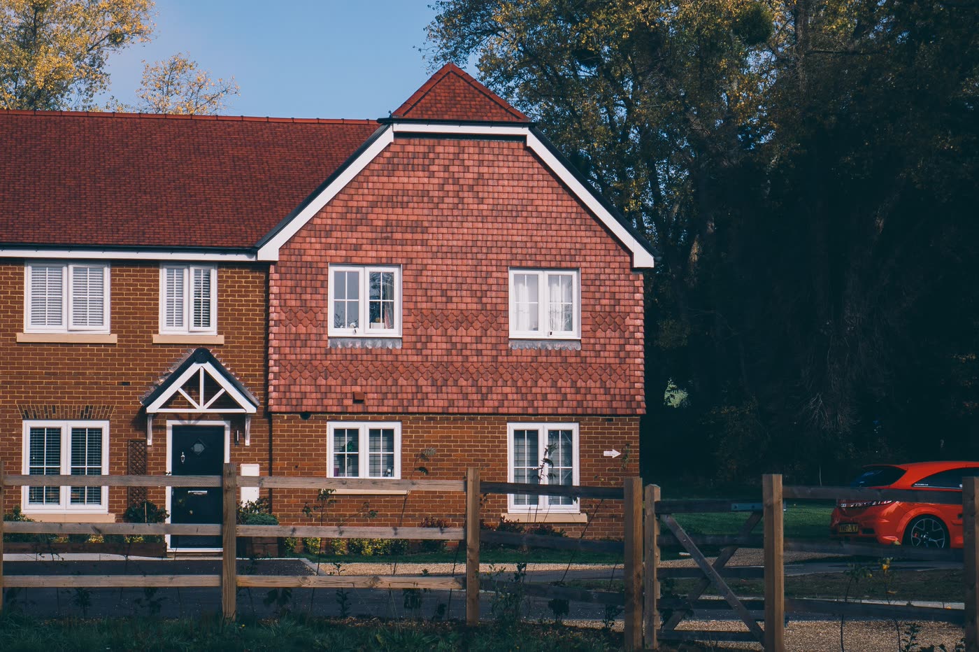 A red-brick UK semi with tile hanging to the upper storey and a block paved frontage