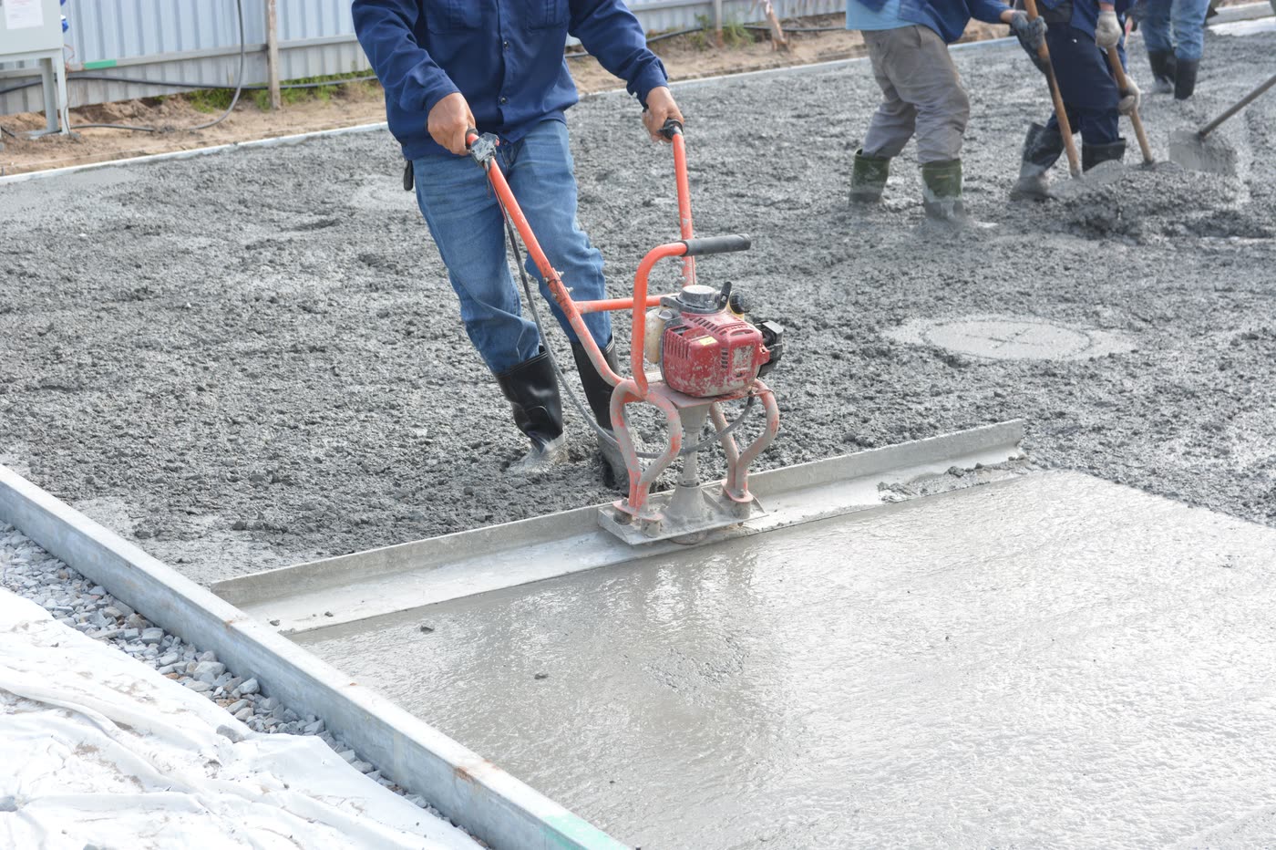 A power screed levelling freshly poured concrete over steel reinforcement