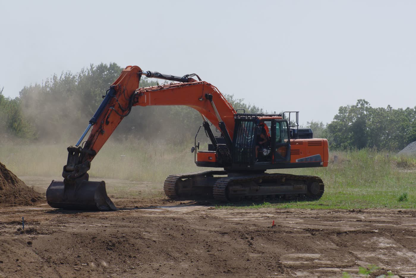 An excavator levelling ground at an outdoor construction site