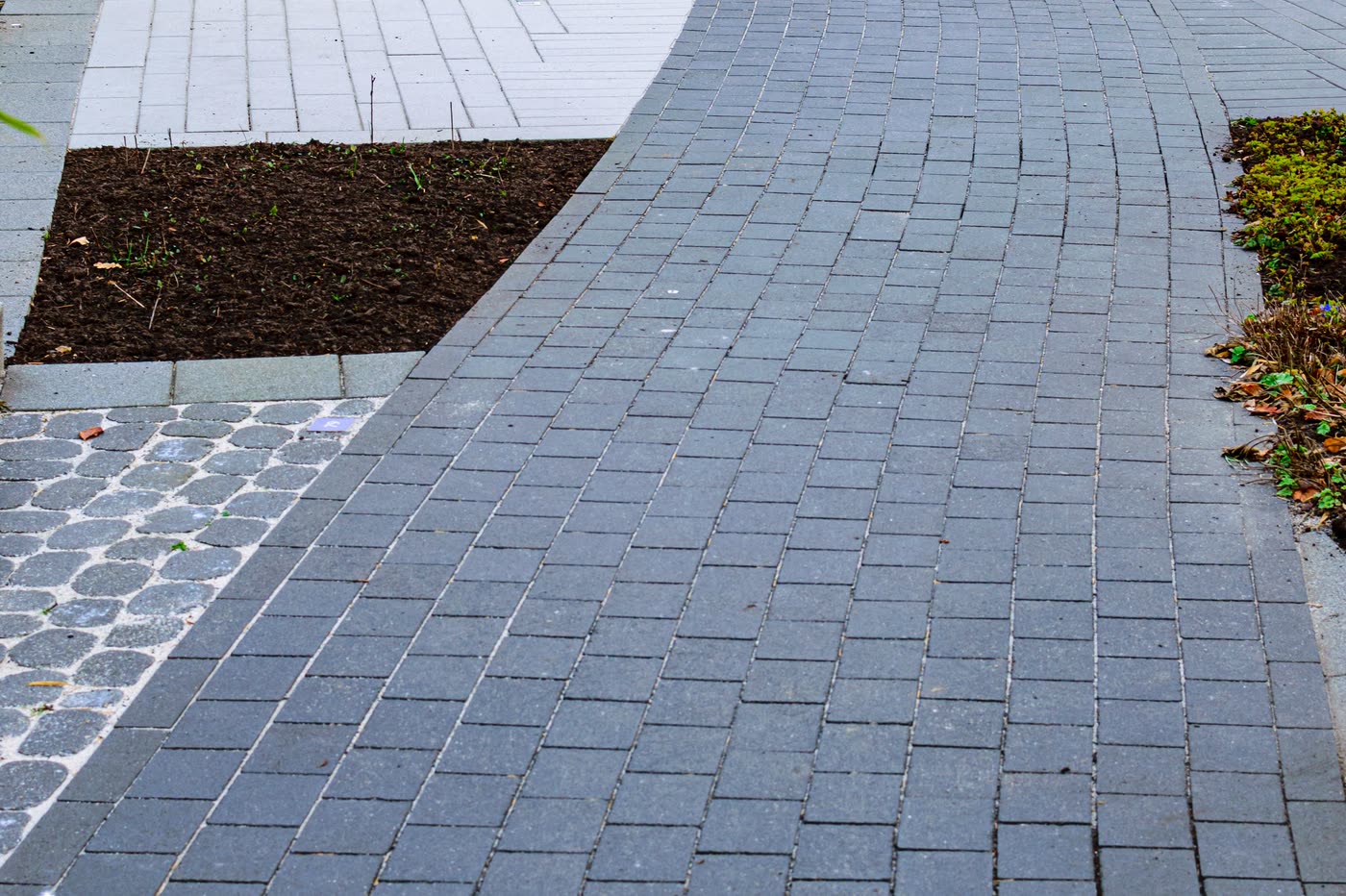 Block paving laid to a sweeping curve against a red brick wall