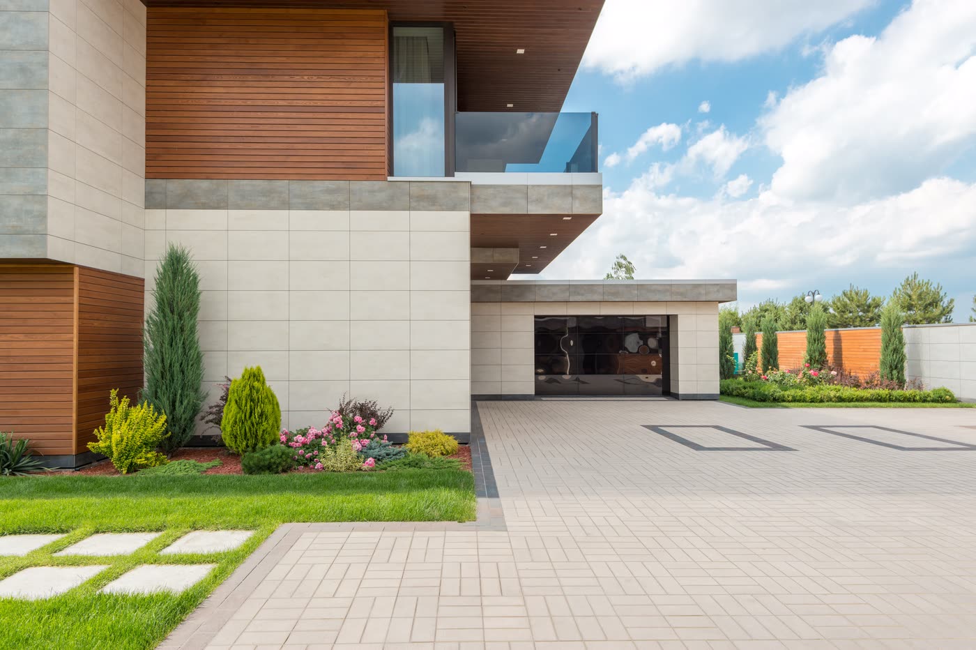 Large-format paving with a contrasting inlaid border meeting a planted bed